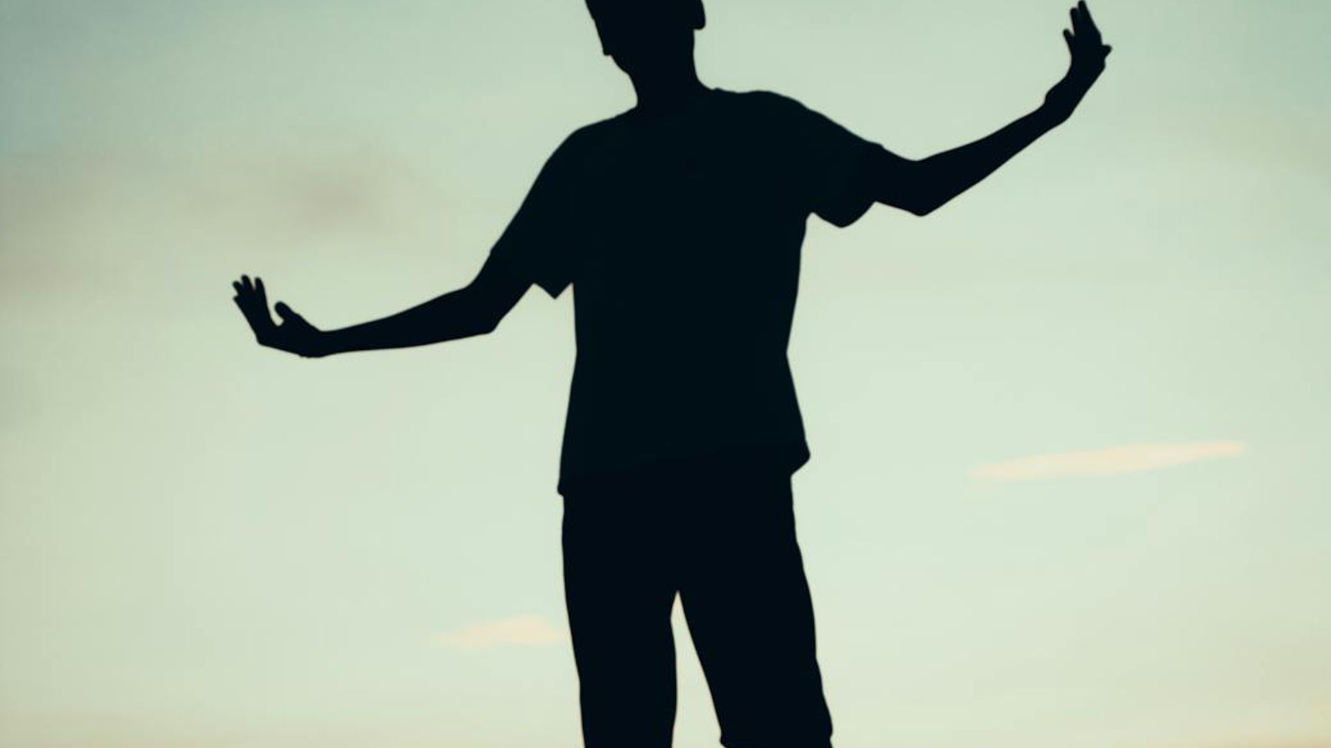 Silhouette of a person in a calm yoga pose against a dark, serene background.
